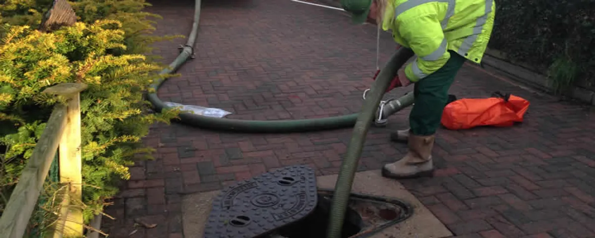 Septic tank cleaning technician servicing a septic tank with a vacuum hose in Albany, NY
